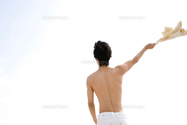 ｔシャツを手で振り回す男性の後姿 の写真素材 イラスト素材 アマナイメージズ