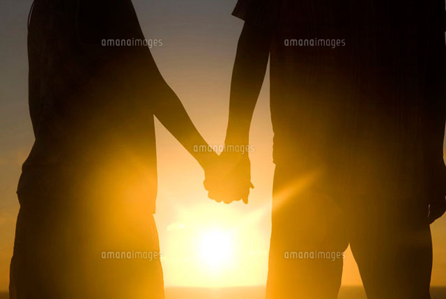 夕暮れに手を繋ぐカップルのシルエット の写真素材 イラスト素材 アマナイメージズ