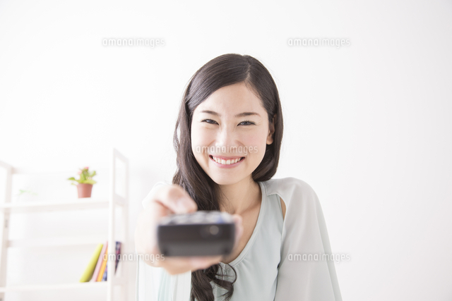 リモコンを触る女性 の写真素材 イラスト素材 アマナイメージズ