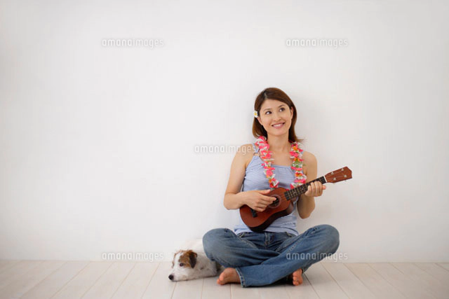 床に座ってウクレレを弾く女性[11038001747]の写真・イラスト素材