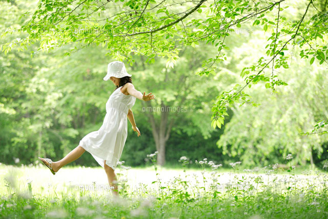 野原を歩く白いワンピースの女性 の写真素材 イラスト素材 アマナイメージズ