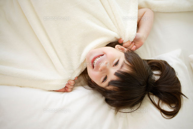 ベットに寝転がる女の子 の写真素材 イラスト素材 アマナイメージズ