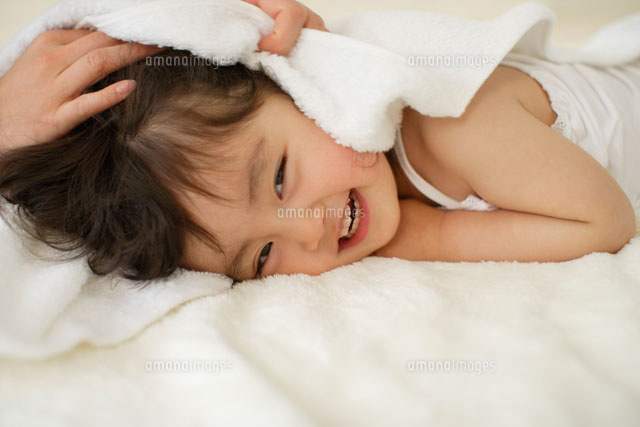 ブランケットの上でまっ白なタオルに包まれる女の子 の写真素材 イラスト素材 アマナイメージズ