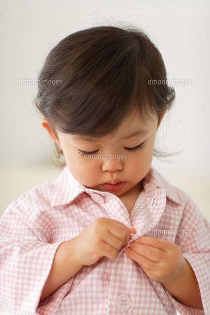 パジャマのボタンを掛ける女の子 の写真素材 イラスト素材 アマナイメージズ