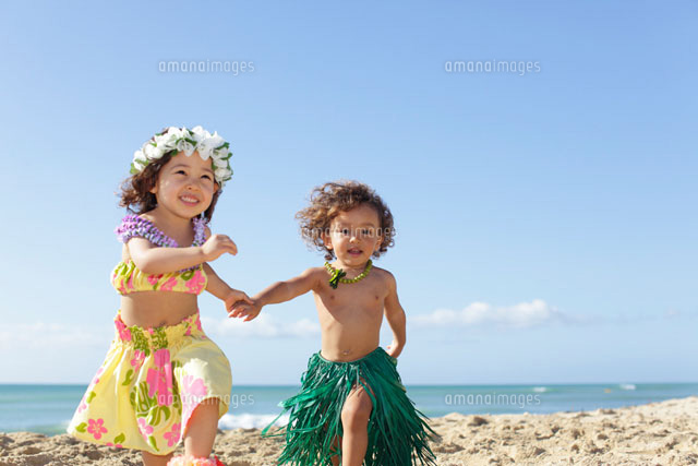 フラダンスの衣装を着て海岸を手を繋いで走るハーフの子ども達 の写真素材 イラスト素材 アマナイメージズ