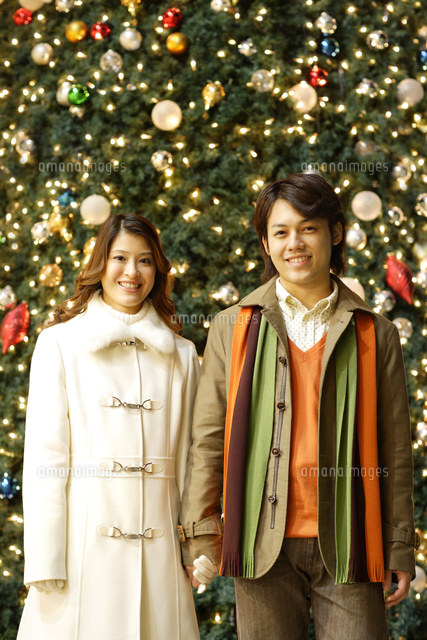 クリスマスツリー前のグループ写真 クリスマスツリーの前で手をつなぐカップル[11038014181]の写真