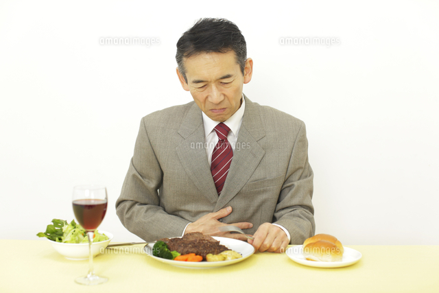 食事中に胃もたれを感じる男性 の写真素材 イラスト素材 アマナイメージズ