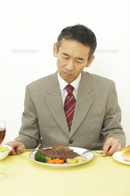 ステーキを前に食欲不振を感じる男性 の写真素材 イラスト素材 アマナイメージズ