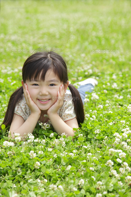 緑のクローバーの上で寝転がる女の子 の写真素材 イラスト素材 アマナイメージズ