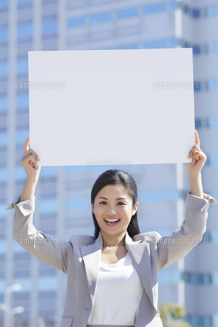 ビル街でホワイトボードを持つビジネスウーマン の写真素材 イラスト素材 アマナイメージズ