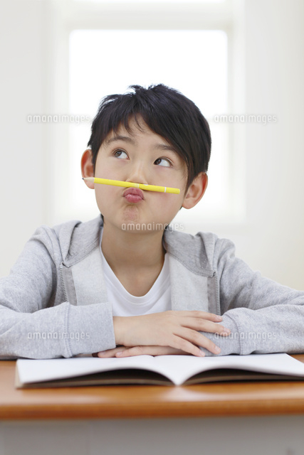 鉛筆を鼻の下に乗せて考える男の子 の写真素材 イラスト素材 アマナイメージズ