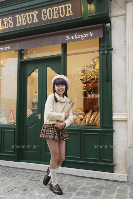 パン屋の前に立つ女の子 の写真素材 イラスト素材 アマナイメージズ