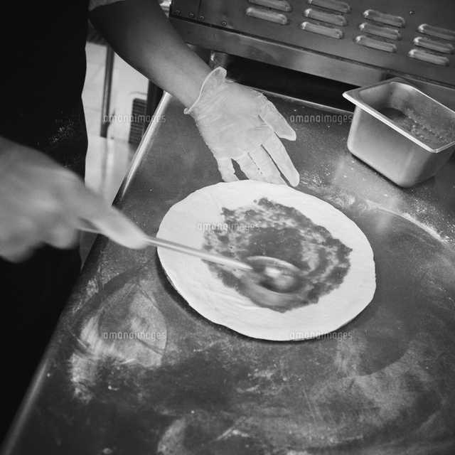 ピザ生地にソースをのせる人の手元 の写真素材 イラスト素材 アマナイメージズ