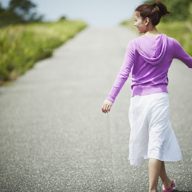 道を歩く女性の後姿 の写真素材 イラスト素材 アマナイメージズ