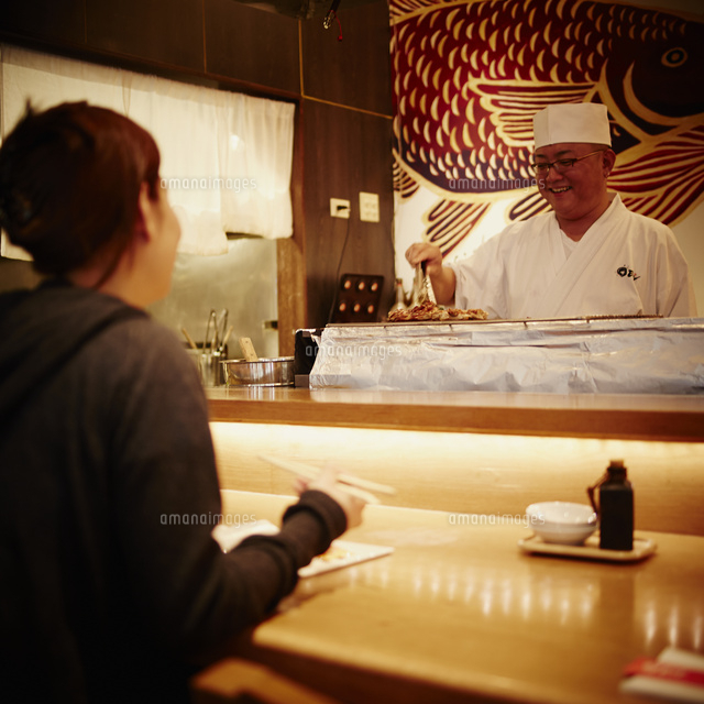 カウンターで向い合う料理人と女性客 の写真素材 イラスト素材 アマナイメージズ