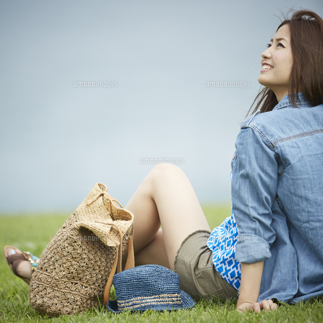 芝生の上に座り空を見上げる女性 の写真素材 イラスト素材 アマナイメージズ