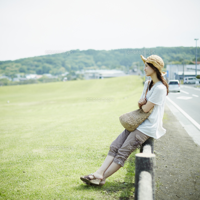 柵に腰かける女性 の写真素材 イラスト素材 アマナイメージズ