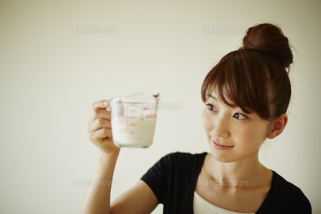 計量カップで牛乳を量る女性 の写真素材 イラスト素材 アマナイメージズ