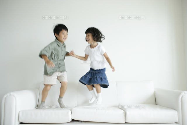 ソファで跳ねる男の子と女の子 の写真素材 イラスト素材 アマナイメージズ
