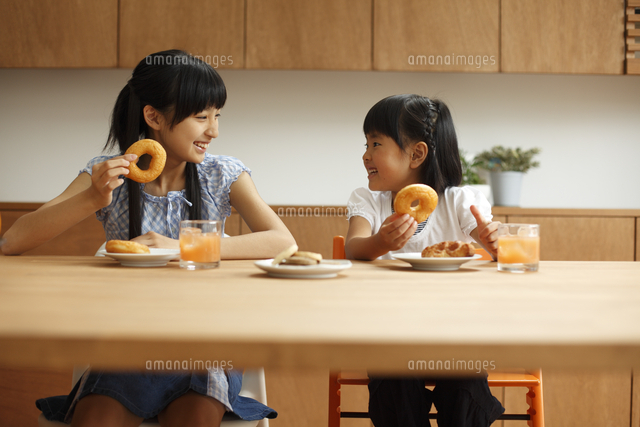 おやつを食べる姉妹 の写真素材 イラスト素材 アマナイメージズ