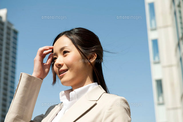 オフィス街で髪の毛をかきあげるスーツ姿の女性 の写真素材 イラスト素材 アマナイメージズ