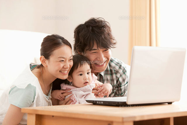 笑顔でパソコンの画面を見つめる赤ちゃんと若い夫婦 の写真素材 イラスト素材 アマナイメージズ