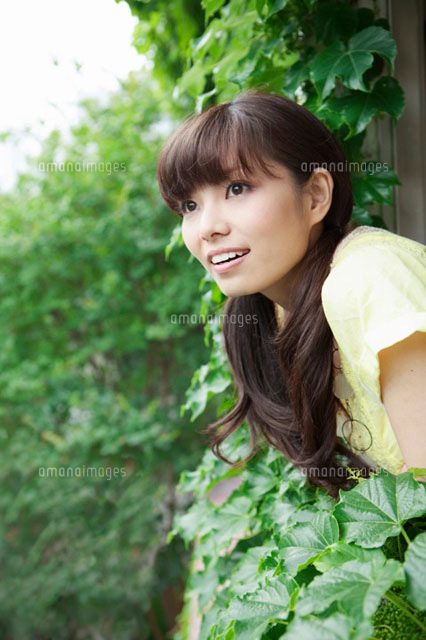窓から身を乗り出し遠くを見つめる若い女性 の写真素材 イラスト素材 アマナイメージズ