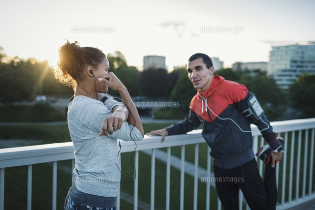 Friends exercising while standing by railing at sidewalk[11081006756]の ...