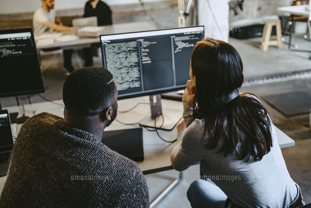 Male and female programmers coding over computer in creative office ...