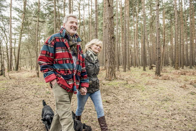Senior couple enjoying a walk in the woods with their dogs.[11082001622 ...