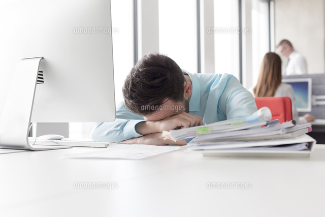 Frustrated Businessman With Head Down Next To Stack Of Reports On Desk の写真素材 イラスト素材 アマナイメージズ