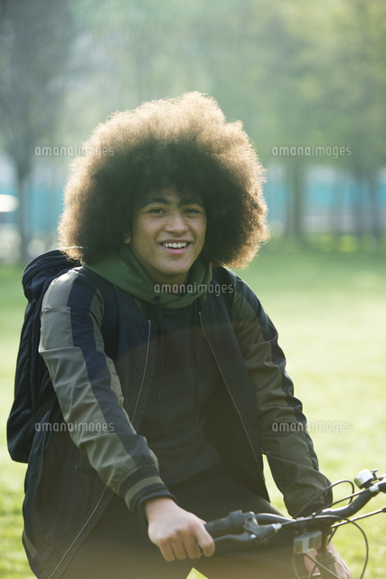 Portrait Happy Young Man With Afro On Bicycle In Park の写真素材 イラスト素材 アマナイメージズ