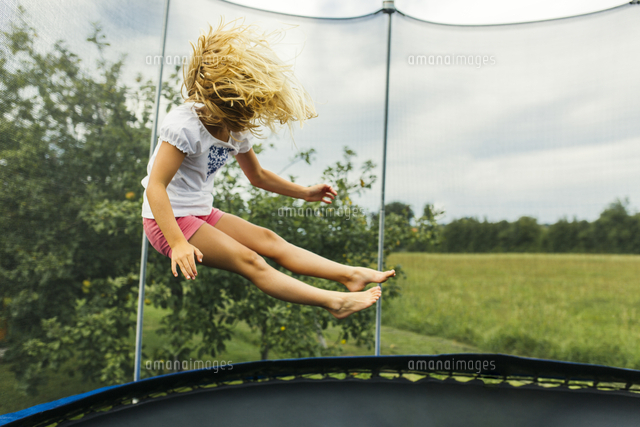 Girl Bouncing On Trampoline の写真素材 イラスト素材 アマナイメージズ