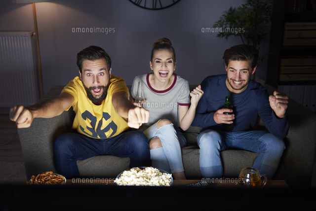 Excited Friends Sitting On The Sofa Watching Tv の写真素材 イラスト 素材 アマナイメージズ