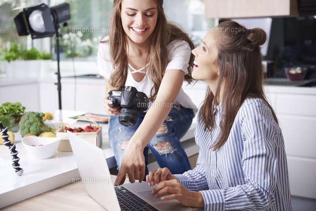 Happy bloggers using laptop in kitchen[11094064736]の写真素材・イラスト素材｜アマナイメージズ