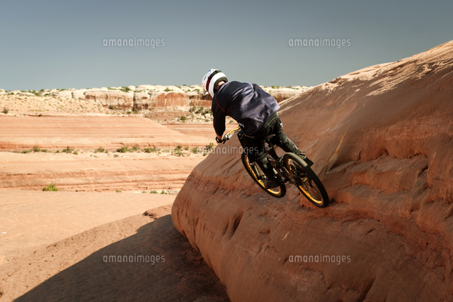 Downhill biker riding on rock[11100010454]の写真素材・イラスト素材｜アマナイメージズ