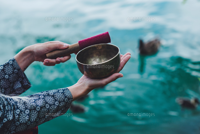 Cropped Image Of Hand Holding Rin Gong Over Lake の写真素材 イラスト 素材 アマナイメージズ