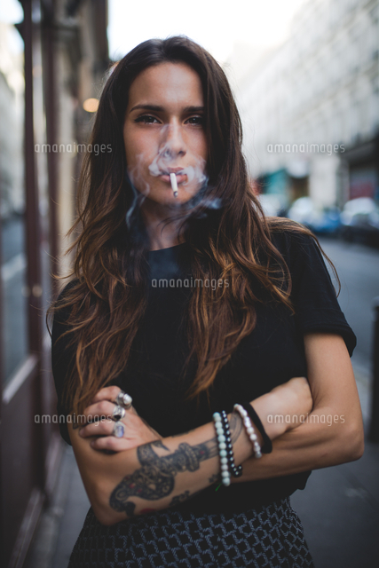 Portrait Of Young Woman Smoking While Standing On Footpath の写真素材 イラスト素材 アマナイメージズ