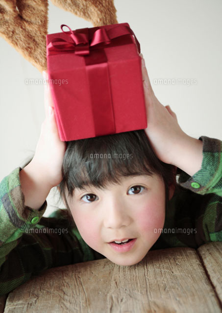 頭の上にプレゼントを乗せた女の子 の写真素材 イラスト素材 アマナイメージズ