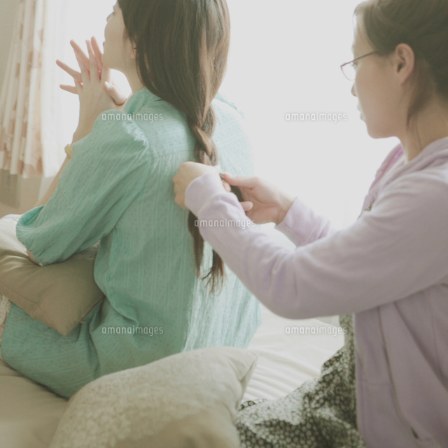 友達の髪を三つ編みにする女性 の写真素材 イラスト素材 アマナイメージズ