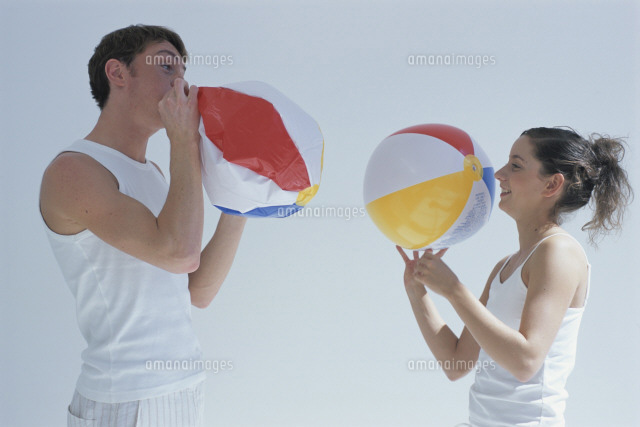 ビーチボールを膨らませる男女 の写真素材 イラスト素材 アマナイメージズ
