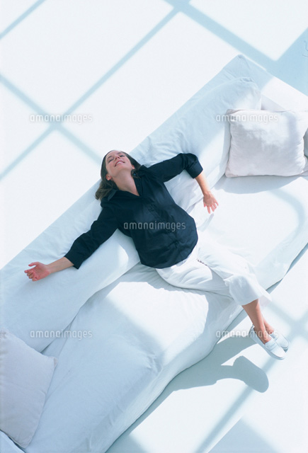 白いソファにもたれた女性 の写真素材 イラスト素材 アマナイメージズ