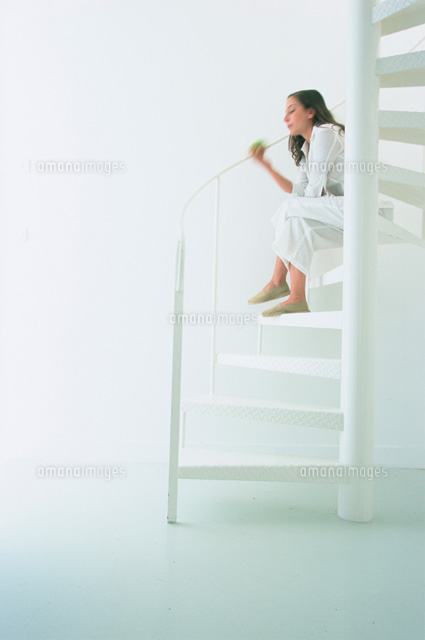 白い螺旋階段に座る女性 の写真素材 イラスト素材 アマナイメージズ