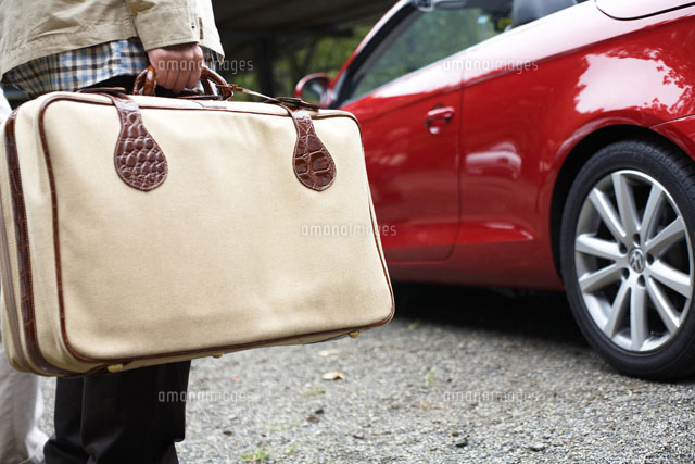 トランクを持った男性と赤い車 の写真素材 イラスト素材 アマナイメージズ