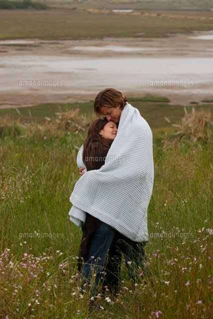 草原で一枚の毛布に包まるカップル a の写真素材 イラスト素材 アマナイメージズ