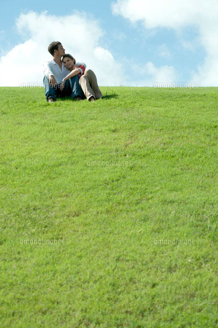 芝生の上に座って女性を抱き寄せる男性 a の写真素材 イラスト素材 アマナイメージズ