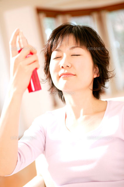 顔にスプレーする女性 の写真素材 イラスト素材 アマナイメージズ
