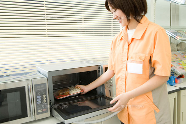 弁当をレンジに入れるコンビニの店員 の写真素材 イラスト素材 アマナイメージズ