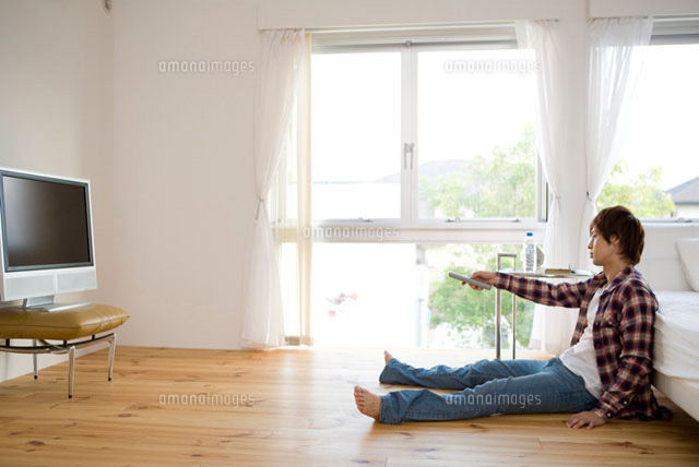 床に座りリモコンをテレビに向ける男性 の写真素材 イラスト素材 アマナイメージズ