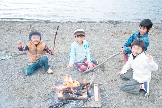 湖畔でおこした焚火を囲む4人の男の子 の写真素材 イラスト素材 アマナイメージズ